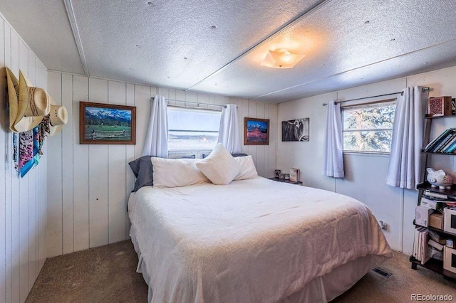 carpeted bedroom with a textured ceiling and wooden walls