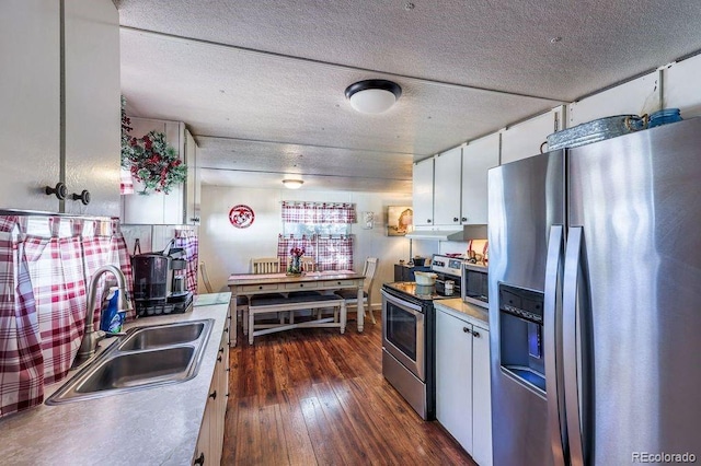 kitchen with white cabinetry, sink, dark hardwood / wood-style floors, a textured ceiling, and appliances with stainless steel finishes