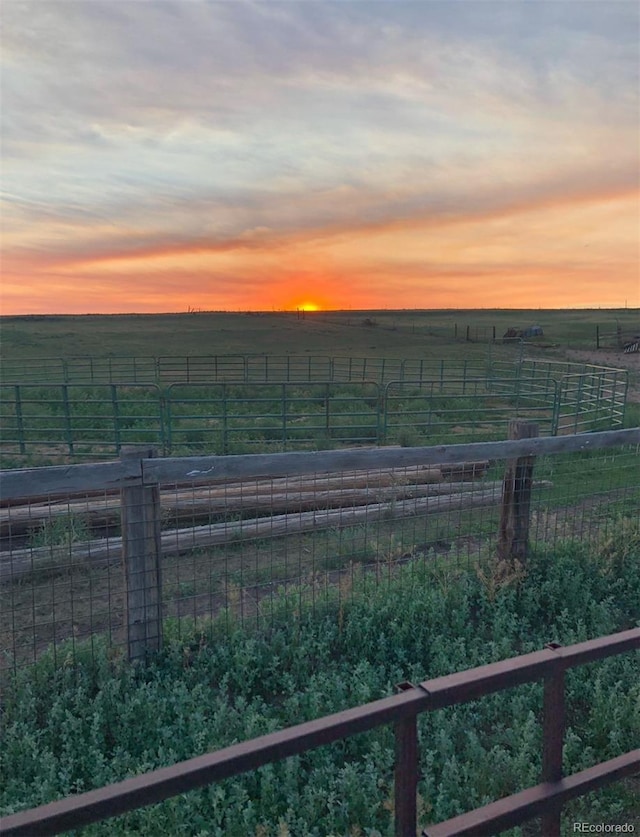 yard at dusk featuring a rural view