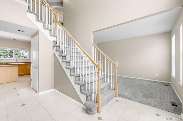staircase with tile patterned flooring, baseboards, and carpet flooring