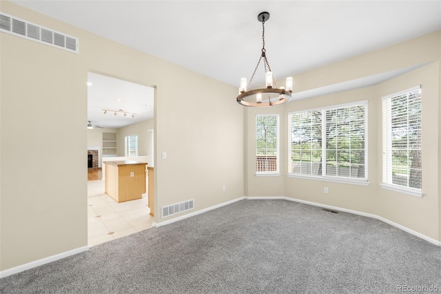 unfurnished room with light carpet, a chandelier, baseboards, a fireplace, and light tile patterned flooring