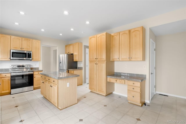 kitchen with appliances with stainless steel finishes, light brown cabinetry, recessed lighting, baseboards, and a center island