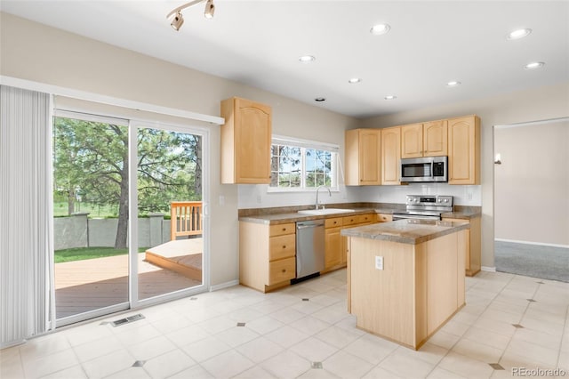 kitchen featuring light brown cabinetry, stainless steel appliances, a kitchen island, recessed lighting, and a sink