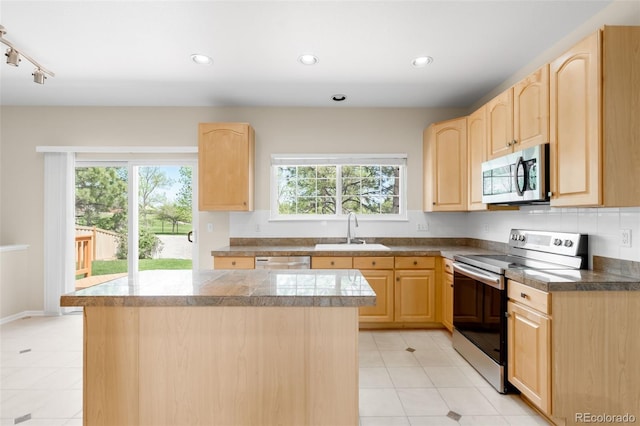 kitchen featuring appliances with stainless steel finishes, light brown cabinets, a sink, tile counters, and a kitchen island
