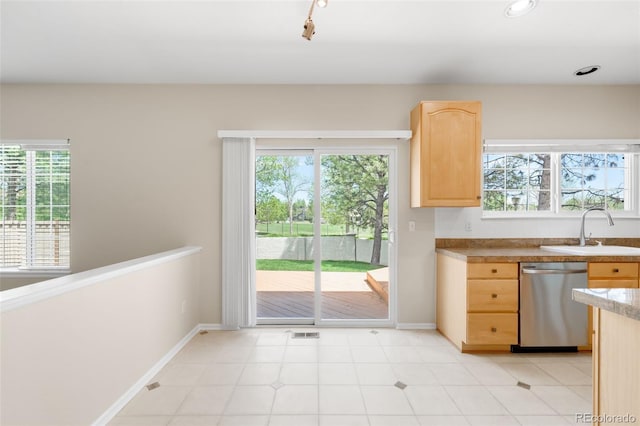 kitchen with light brown cabinetry, dishwasher, a sink, and plenty of natural light