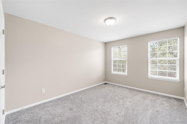 carpeted spare room featuring baseboards