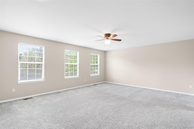 empty room with a ceiling fan, healthy amount of natural light, baseboards, and carpet flooring