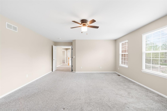 empty room with a ceiling fan, baseboards, and light colored carpet