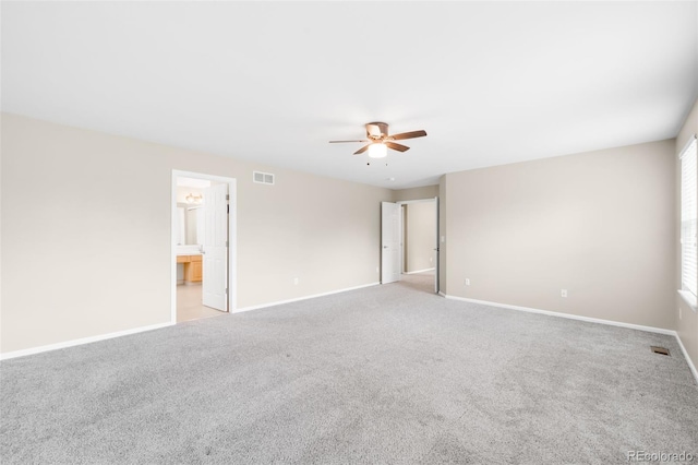 unfurnished bedroom with light colored carpet, baseboards, ceiling fan, and connected bathroom
