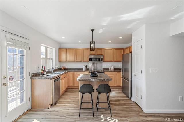 kitchen featuring dark stone countertops, stainless steel appliances, a center island, a kitchen bar, and decorative light fixtures