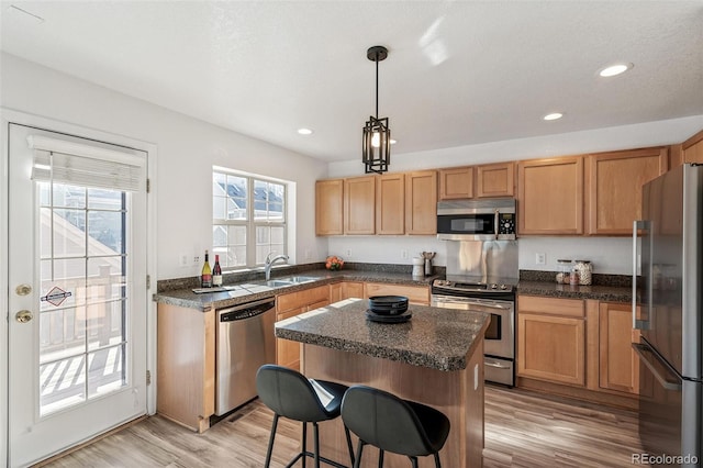 kitchen with sink, decorative light fixtures, a center island, light hardwood / wood-style flooring, and appliances with stainless steel finishes