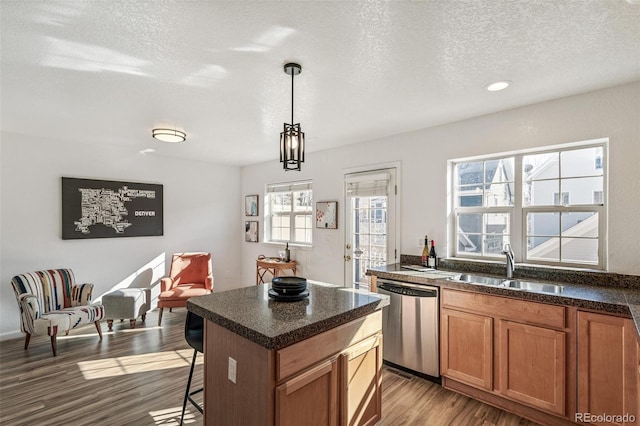 kitchen with pendant lighting, dishwasher, sink, hardwood / wood-style flooring, and a center island