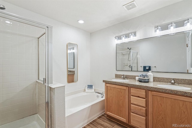 bathroom with hardwood / wood-style flooring, vanity, and shower with separate bathtub