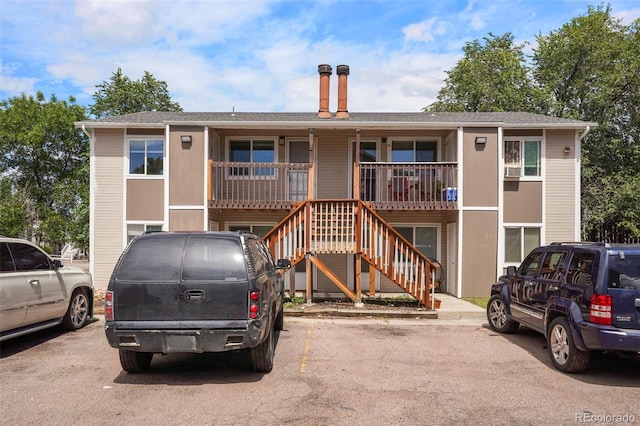 view of property with uncovered parking and stairs