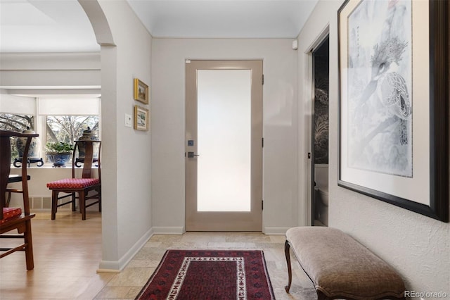 foyer with arched walkways and baseboards