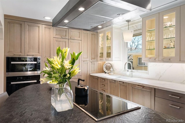 kitchen featuring double oven, black electric cooktop, a sink, backsplash, and dark stone countertops