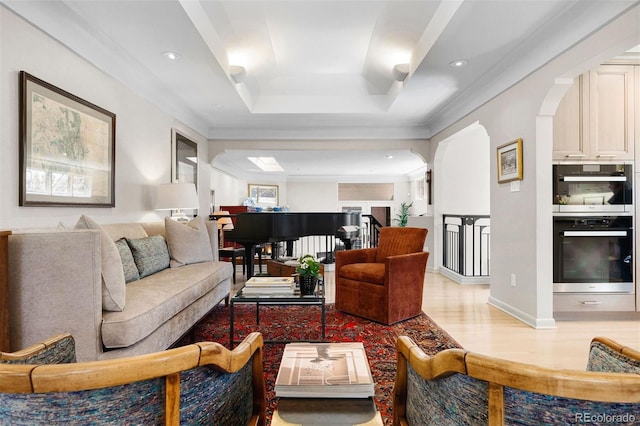 living area with arched walkways, light wood-style flooring, recessed lighting, baseboards, and a raised ceiling