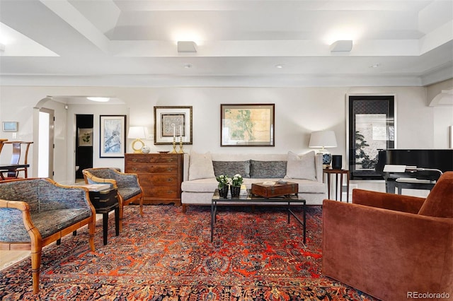 living area with arched walkways and a tray ceiling