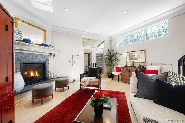 living area with ornamental molding, wood finished floors, and a high end fireplace