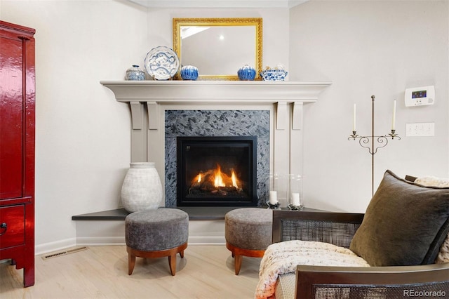 sitting room with baseboards, a fireplace, visible vents, and wood finished floors