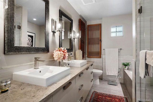 bathroom with double vanity, a stall shower, tile walls, and a sink