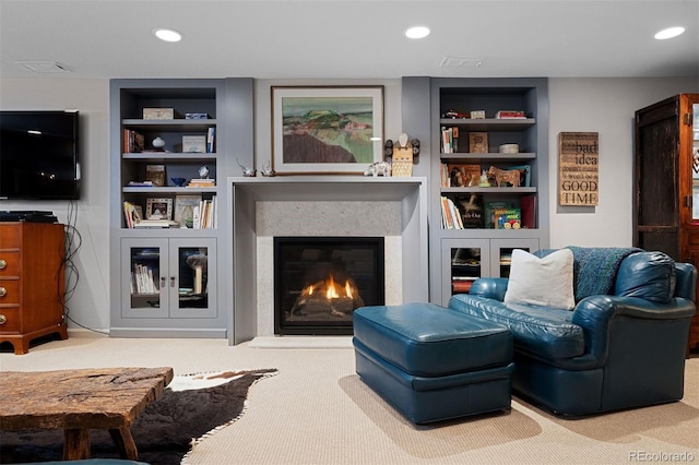 living area featuring built in features, a glass covered fireplace, carpet floors, and recessed lighting