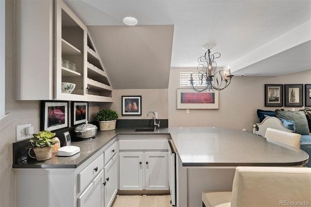 kitchen with white cabinets, a breakfast bar area, open floor plan, a peninsula, and a sink