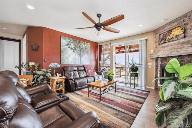 living area with a ceiling fan, recessed lighting, a large fireplace, and wood finished floors