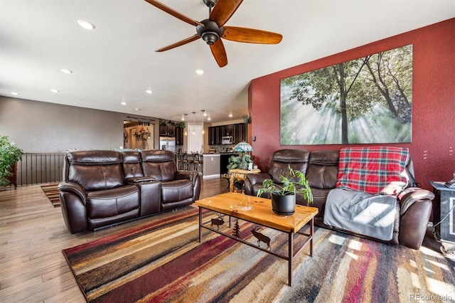living area featuring light wood finished floors, a ceiling fan, and recessed lighting