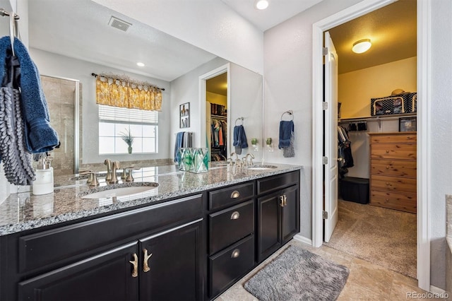 bathroom featuring double vanity, visible vents, a spacious closet, and a sink