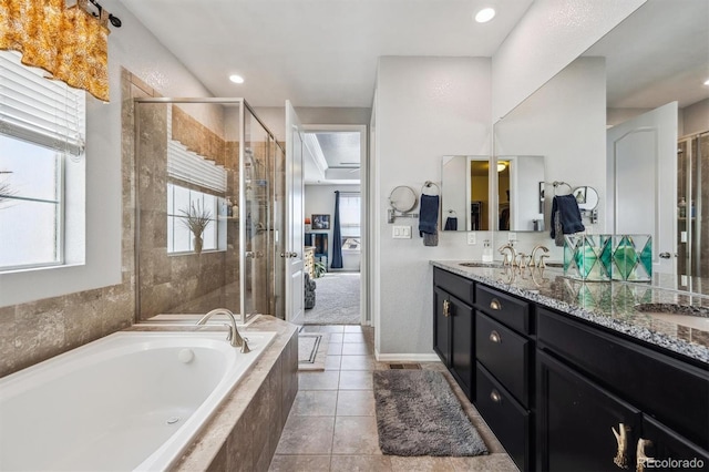 bathroom featuring a shower stall, a garden tub, double vanity, and a sink
