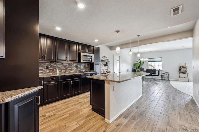kitchen featuring light stone countertops, black dishwasher, light wood finished floors, visible vents, and stainless steel microwave