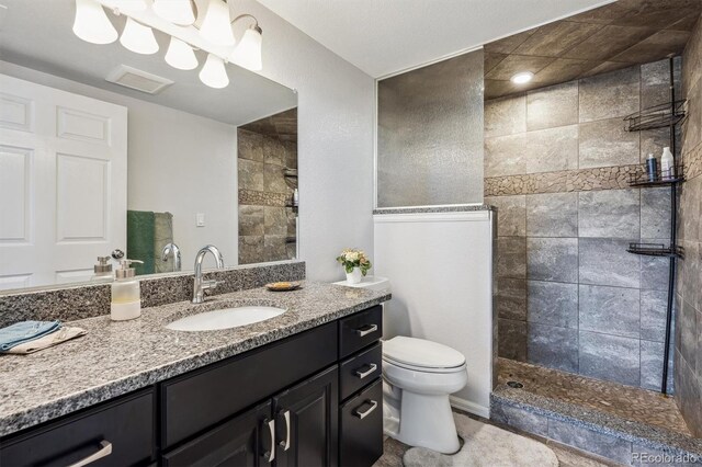 bathroom featuring toilet, visible vents, vanity, and a walk in shower