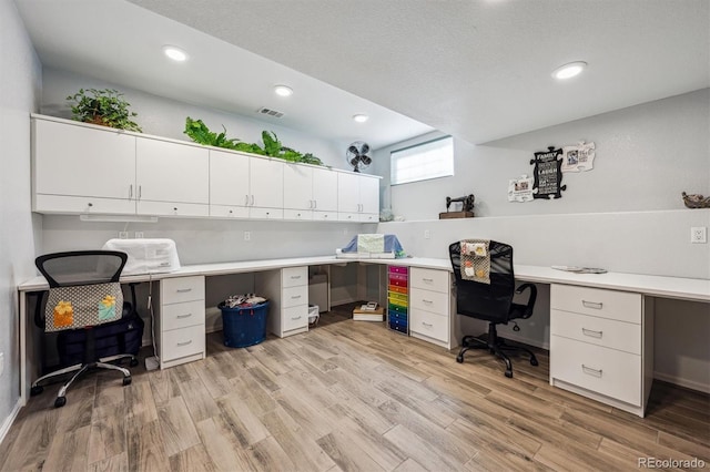 home office with built in study area, light wood-type flooring, visible vents, and recessed lighting