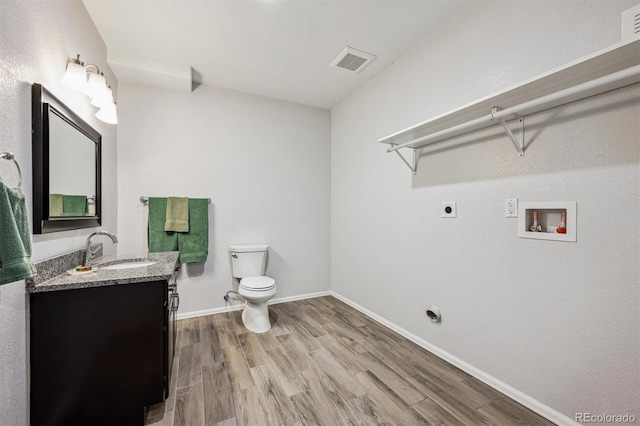 bathroom with toilet, wood finished floors, vanity, visible vents, and baseboards