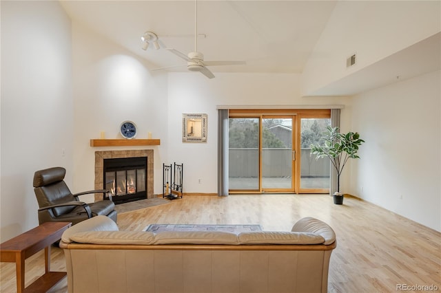 living room with ceiling fan, lofted ceiling, light hardwood / wood-style floors, and a tile fireplace