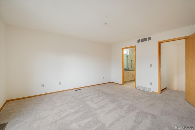 unfurnished bedroom featuring connected bathroom and light colored carpet