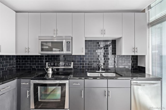 1700 Bassett St Unit 820, Denver, CO 80202 - kitchen with stainless steel appliances, a sink, white cabinetry, backsplash, and dark stone counters