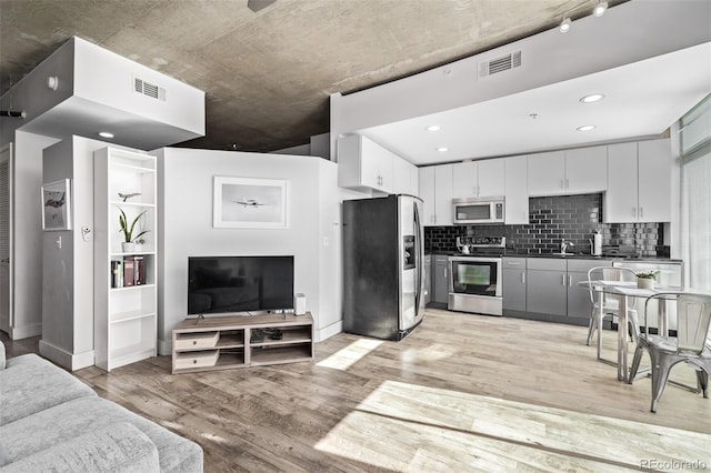 1700 Bassett St Unit 820, Denver, CO 80202 - kitchen with stainless steel appliances, dark countertops, light wood-style flooring, a sink, and tasteful backsplash