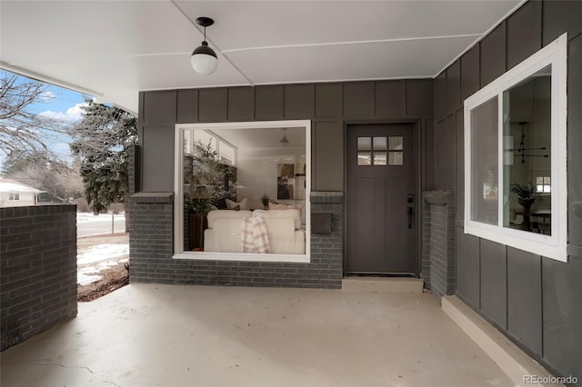 property entrance featuring brick siding, board and batten siding, and a patio