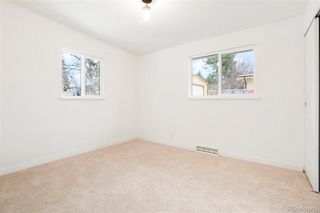 unfurnished room featuring baseboards, a wealth of natural light, visible vents, and light colored carpet