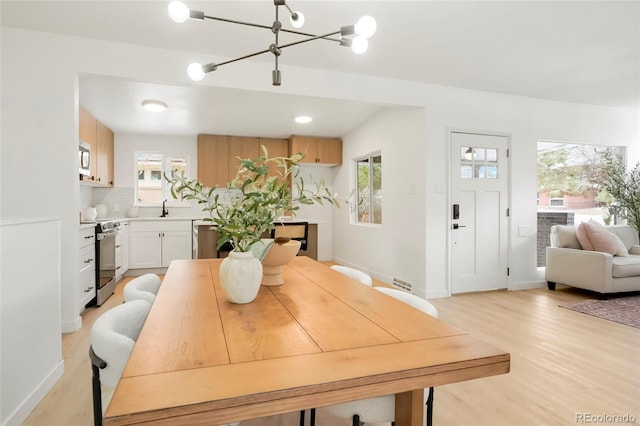 dining area featuring a chandelier, light wood-type flooring, and baseboards