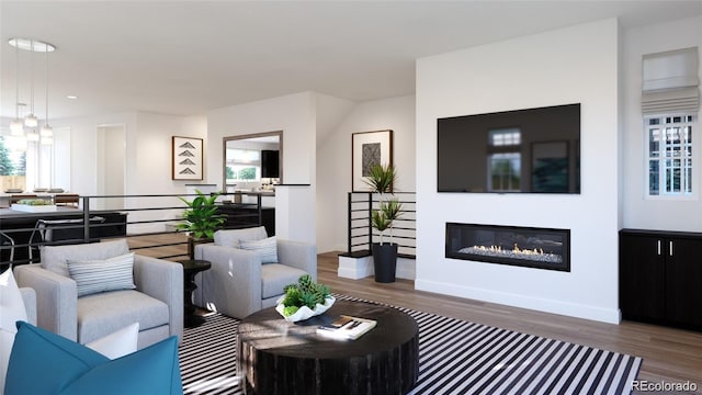 living room with a healthy amount of sunlight, baseboards, wood finished floors, and a glass covered fireplace