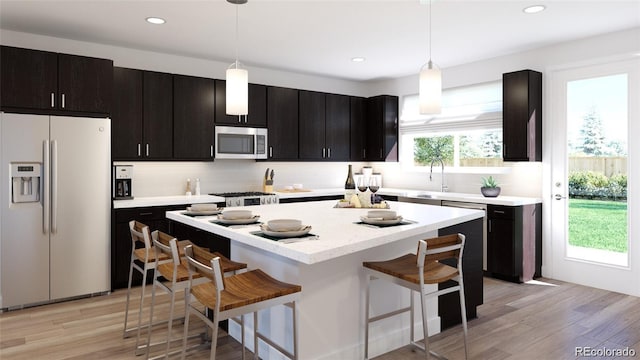 kitchen featuring appliances with stainless steel finishes, decorative light fixtures, backsplash, and a breakfast bar area