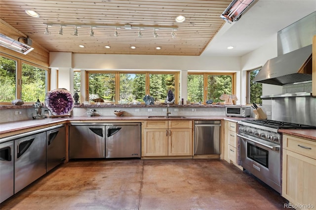 1000 Rangeview Ct, Black Hawk, CO 80422 - kitchen with appliances with stainless steel finishes, wall chimney range hood, light brown cabinetry, concrete floors, and rail lighting