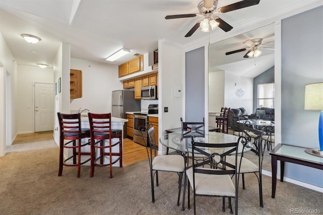 dining area with light colored carpet, vaulted ceiling, and baseboards