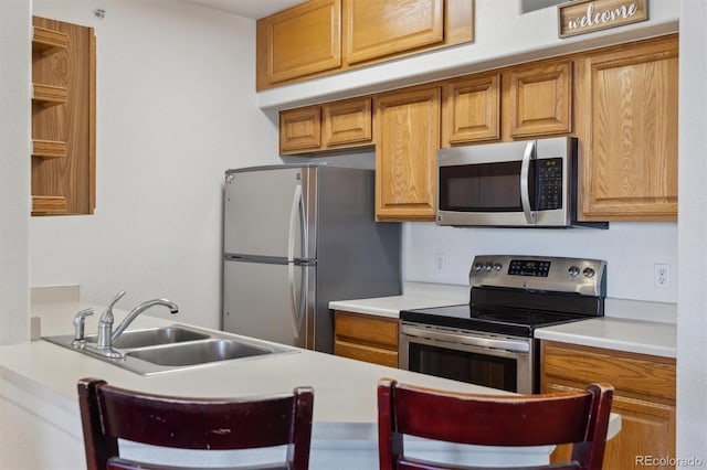 kitchen featuring brown cabinets, stainless steel appliances, a sink, and light countertops