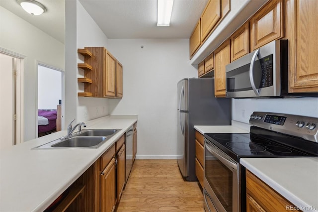 kitchen with open shelves, light countertops, light wood-style flooring, appliances with stainless steel finishes, and a sink