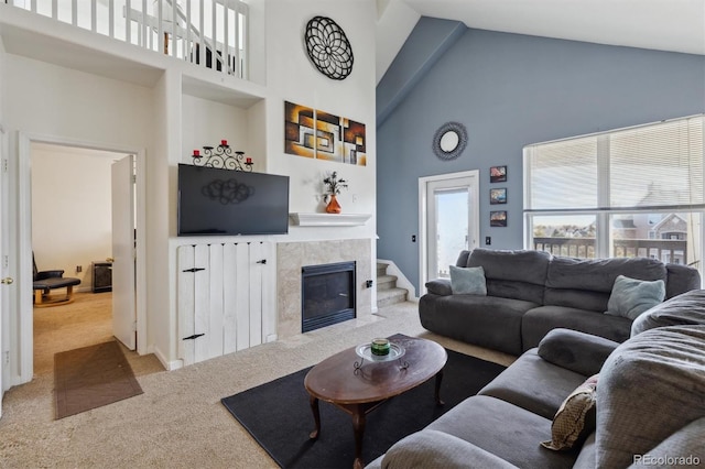 living area with carpet floors, high vaulted ceiling, and a tile fireplace