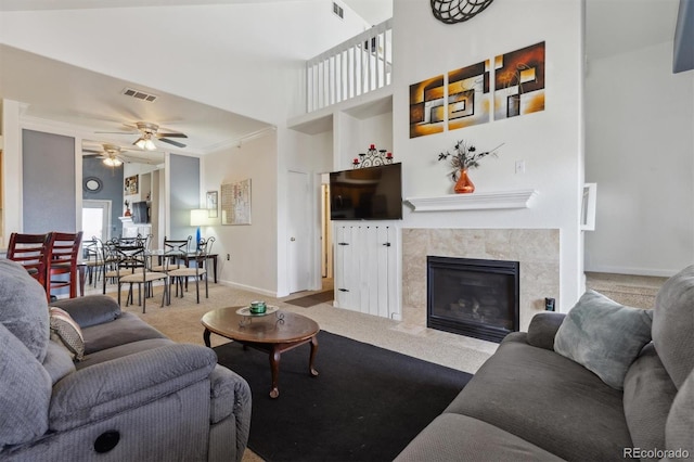 carpeted living room featuring baseboards, a premium fireplace, visible vents, and a ceiling fan